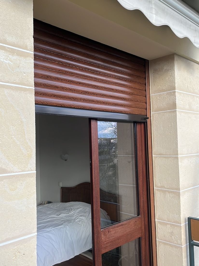 Volet roulant imitation bois installe dans une chambre, vu de l interieur
