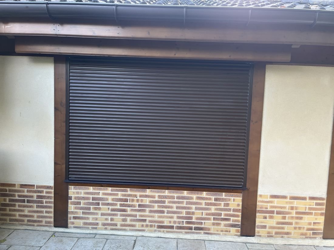 Volet roulant marron installé sur une large fenêtre de maison